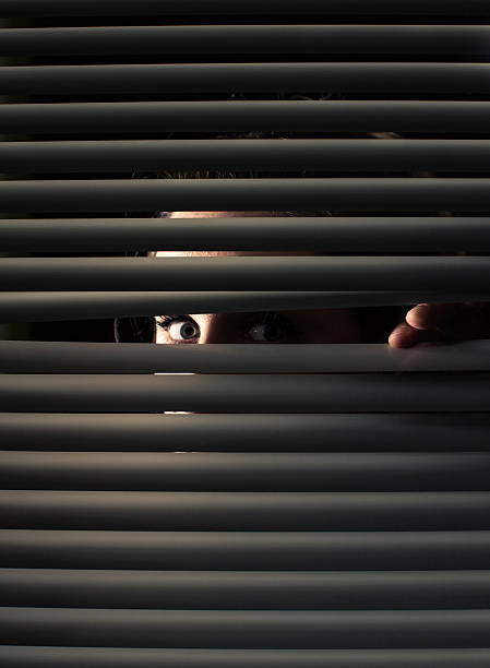 frau schaut durch fenster - hiding human eye fear women stock-fotos und bilder