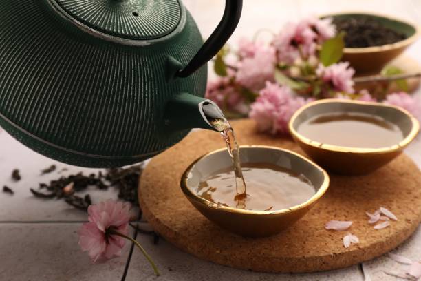 Traditional ceremony. Pouring brewed tea from teapot into cup on tiled table, closeup Traditional ceremony. Pouring brewed tea from teapot into cup on tiled table, closeup pink tea stock pictures, royalty-free photos & images