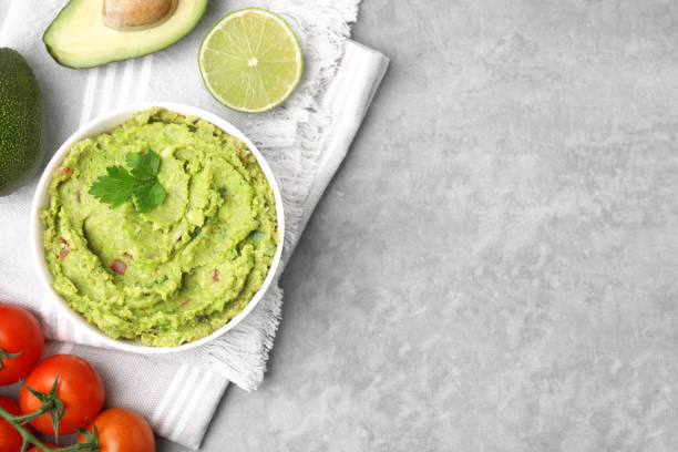 istock Bowl of delicious guacamole and ingredients on grey table, flat lay. Space for text 1713755329