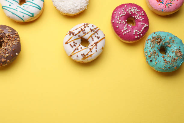 istock Tasty glazed donuts on yellow background, flat lay. Space for text 1713756941
