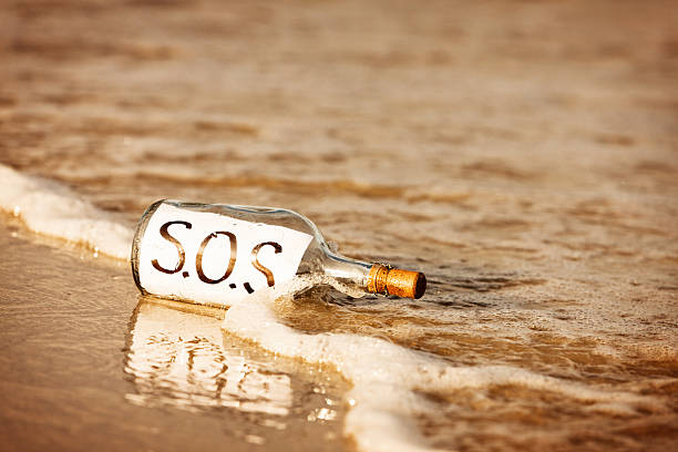 покинутый послание в бутылке на берег — говорит sos - stranded message in a bottle island document стоковые фото и изображения