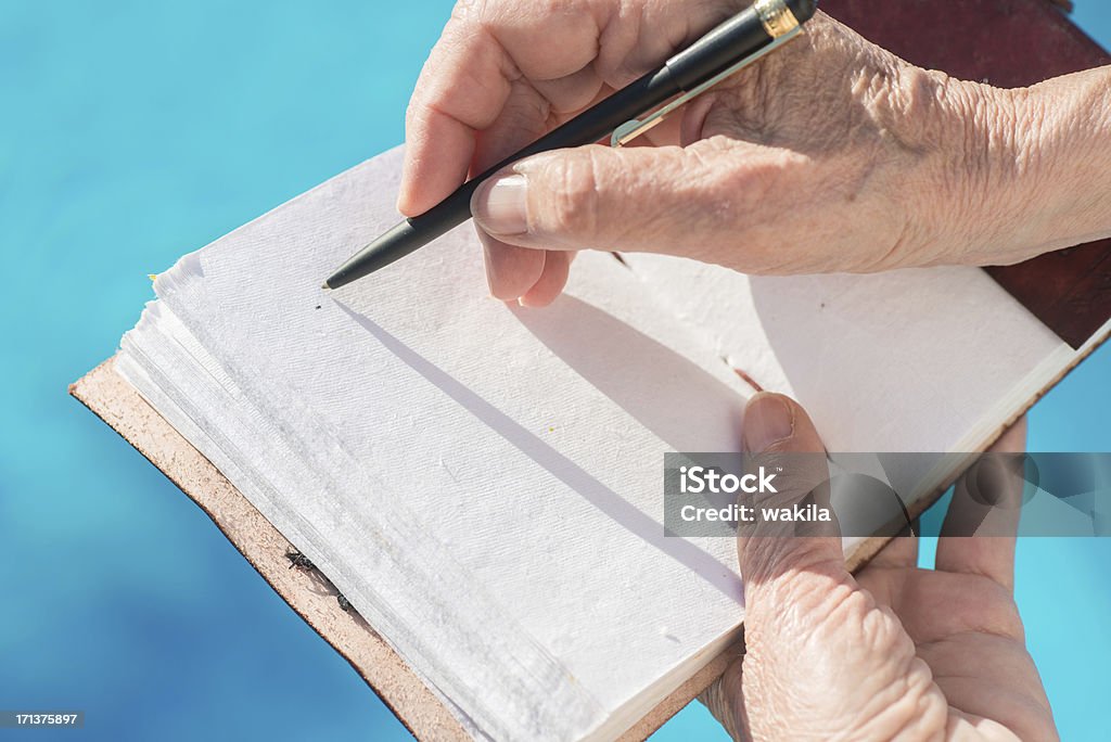 writing in empty leatherbook diary or guestbook at pool writing in diary outside. Book is from the german brand Indiary Author Stock Photo