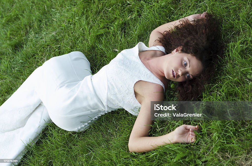 Open eyed bride looking dead on grass. "Horizontal outdoor shot of bride laying on grass, looking dead." Dead Stock Photo