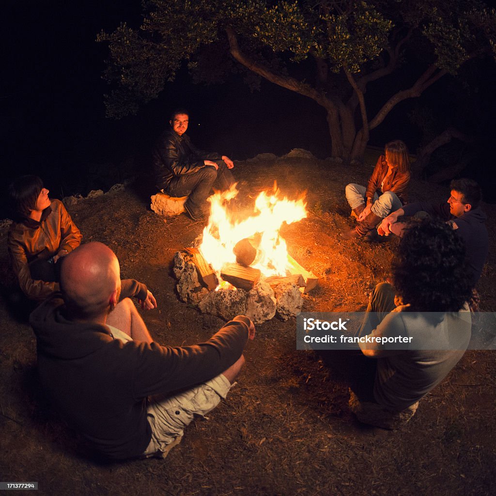 Fuoco di accampamento di amici in cerchio sulla fuoco - Foto stock royalty-free di Fuoco di accampamento