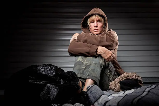 A homeless woman sitting on the ground.