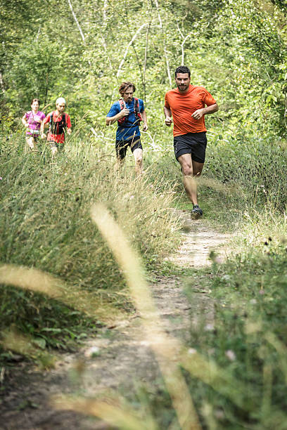 Trail runners running in trail surrounded by tall grass stock photo