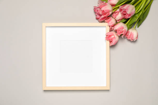 istock Empty photo frame and beautiful tulip flowers on light gray background, flat lay. Mockup for design 1713780622