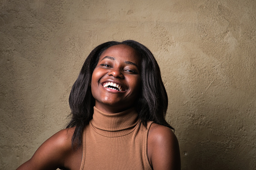 A young African American woman looking at camera and laughing in a studio shot