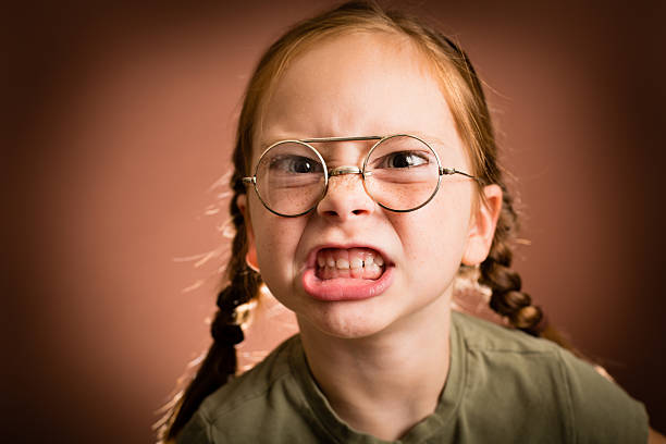 petite fille portant des lunettes pourtant fait dire le visage - cruel photos et images de collection