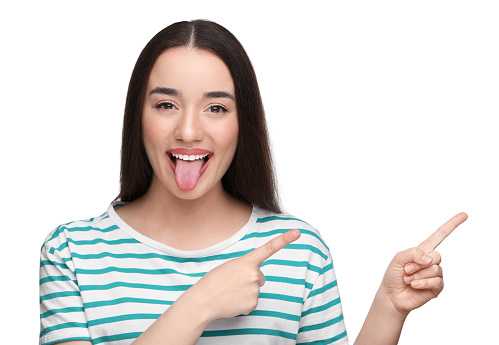Happy woman showing her tongue and pointing at something on white background