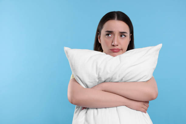 istock Tired young woman with pillow on light blue background, space for text. Insomnia problem 1713783681