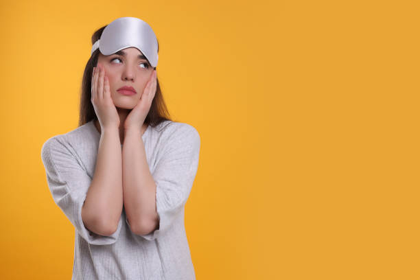 istock Tired young woman with sleep mask on yellow background, space for text. Insomnia problem 1713783779