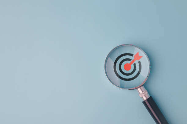 istock Goal board inside magnifying glass to focus on business objectives on blue background and copy space. 1713785565