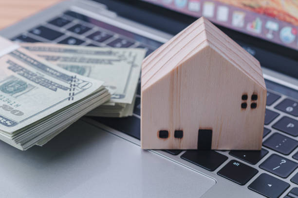 istock Wooden house model and banknotes on tablet keyboard. 1713785703