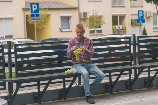 Man in the city, eating ripe autumn grapes outdoors