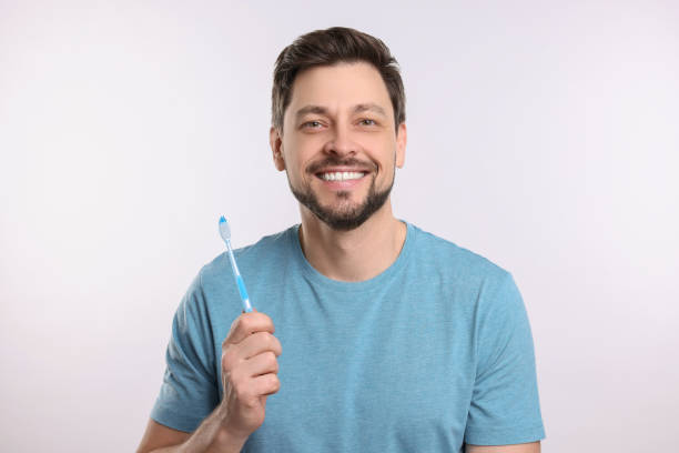 istock Happy man holding plastic toothbrush on white background. Mouth hygiene 1713788528