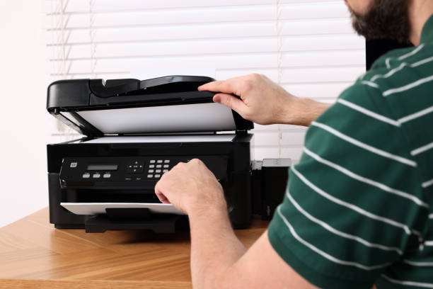 istock Man using modern printer at wooden table indoors, closeup 1713789150