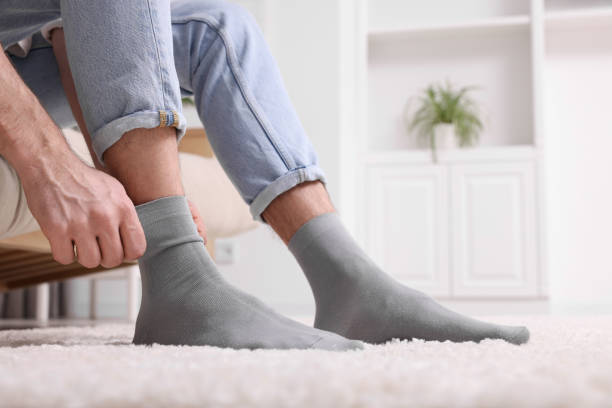 istock Man putting on grey socks at home, closeup. Space for text 1713789689