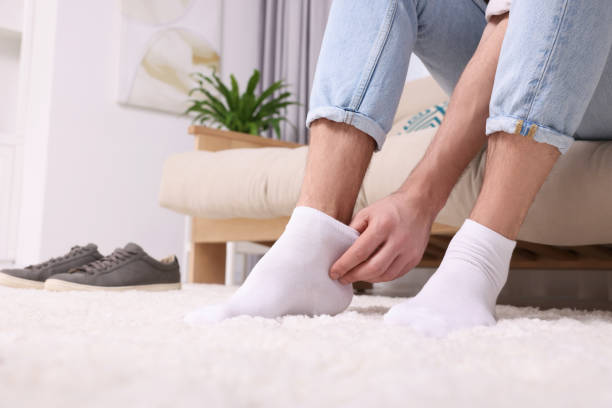 istock Man putting on white socks at home, closeup. Space for text 1713789744