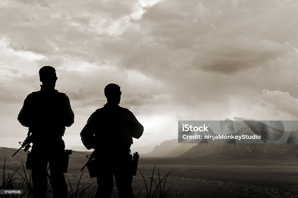 Army Soldiers in the Valley of Death Two military soldiers stand overlooking an ominous valley. Armed Forces Stock Photo