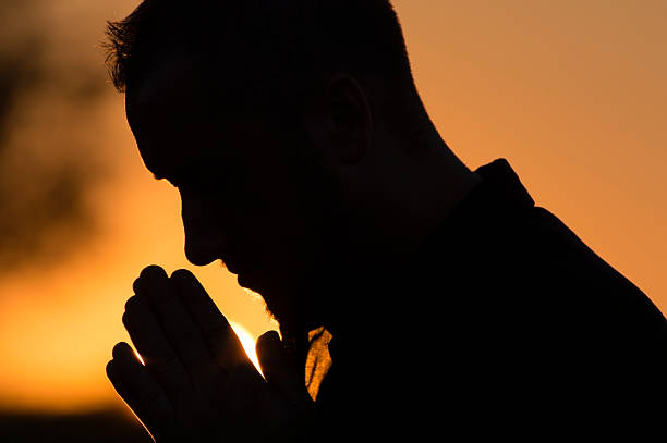 istock Young Man Praying Outside at Sunset 171380139