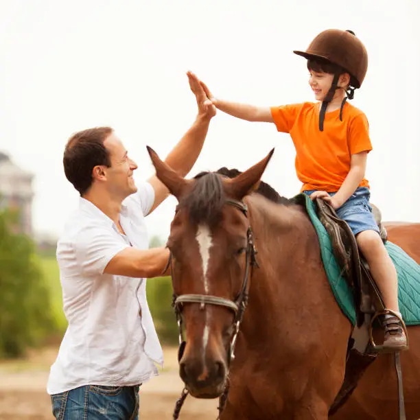 Photo of Child Riding Horse Outdoors.