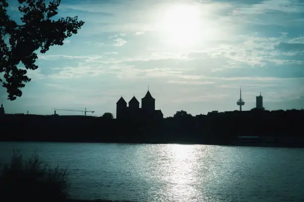 Sunset over Kath. Kirche St. Kunibert Cologne and Rhine river. Silhouette of the left bank of the city of Cologne