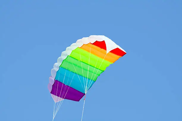 Rainbow colored stunt kite in summer sunshine.