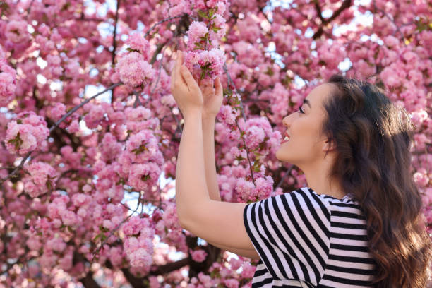 istock Beautiful woman near blossoming sakura tree on spring day 1713816019
