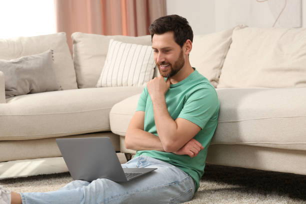 istock Man using laptop on floor near sofa at home 1713816939