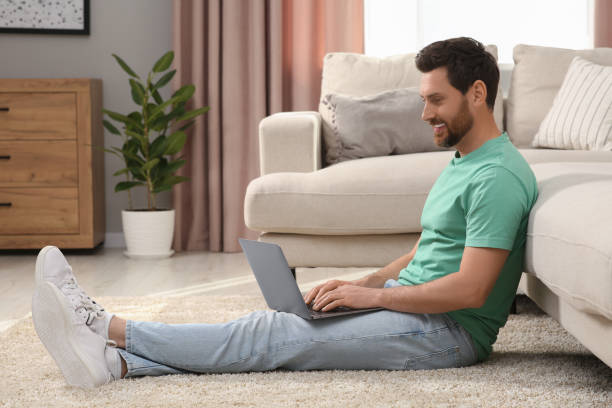istock Man using laptop on floor near sofa at home 1713817118