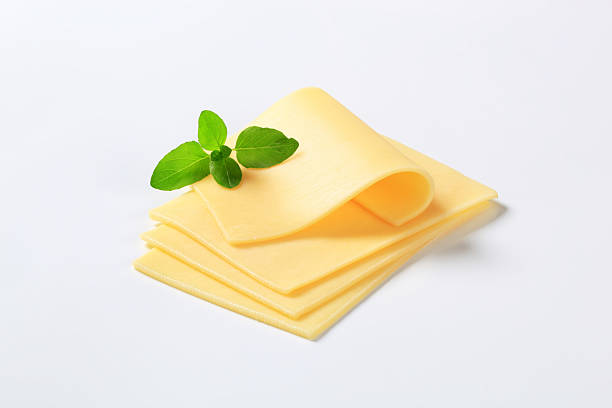 four slices of cheese four thin slices of a fresh cheese decorated with green leaves of a basil edam stock pictures, royalty-free photos & images