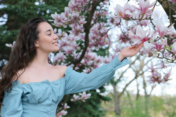 istock Beautiful woman touching blossoming magnolia tree branch on spring day 1713818809
