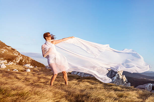 istock Young woman wrapped in white silk on hilltop 171382704