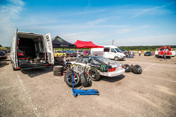 Parked Nissan "Kaunas, Lithuania - June 30, 2012: Kenda tyres team parking place at EEDC event at Nemunas circuit. Car is a Nissan 200SX S13 parked next to teams van. Tyres are out, ready to be changed, driving is waiting to drift a qualification run." monster energy stock pictures, royalty-free photos & images