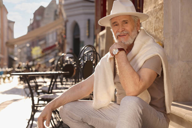 Handsome senior man sitting on doorstep outdoors, space for text