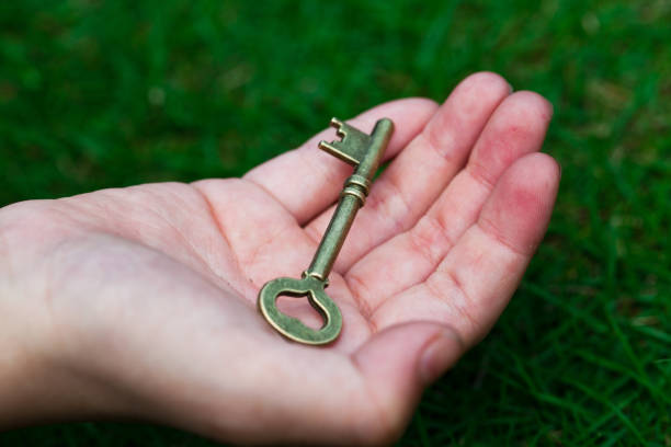 main tenant la clé de la réussite - human hand key giving carrying photos et images de collection