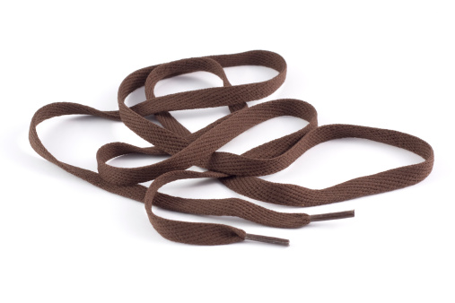 Brown shoe lace isolated on white. Main focus towards the foreground, softer focus towards the back.