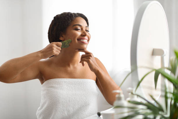 istock Beauty Tools. Happy Black Female Making Face Massage With Gua Sha Scraper 1713849290