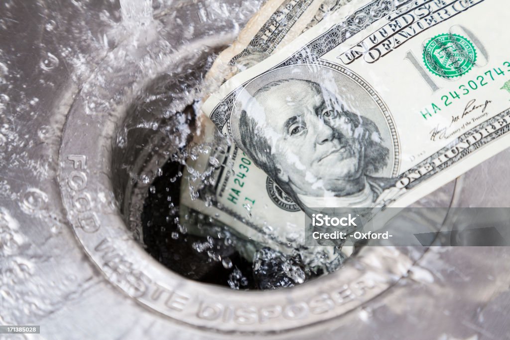 Money Down Drain Money being washed down garbade disposal Excess Stock Photo