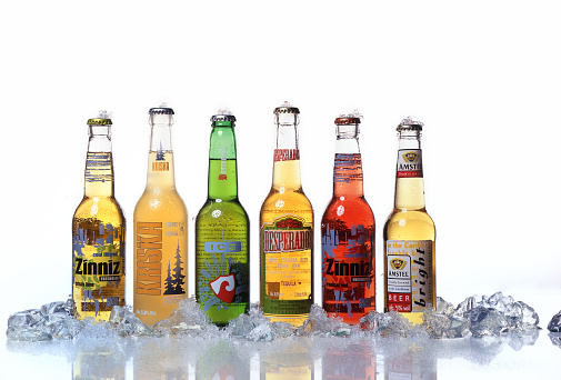 Beer bottles and glasses on light grey background with place for text.
