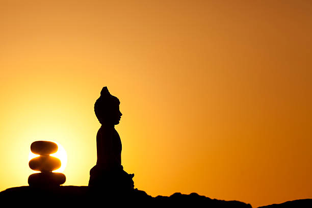 silhouette von buddha-statue und zen-stone pyramid - venerable stock-fotos und bilder