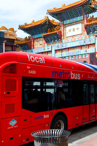 Washington DC, USA - June 13, 2012: A Metrobus, part of the Washington DC public transit system, at a bus stop on H Streetin Chinatown. In the background is the Friendship Archway, which was dedicated in 1986.