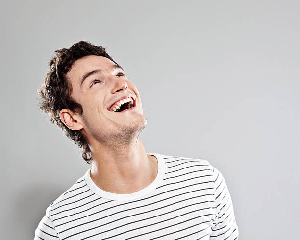 Excited man Portrait of happy young man looking up. Studio shot, grey background. cheesy grin stock pictures, royalty-free photos & images