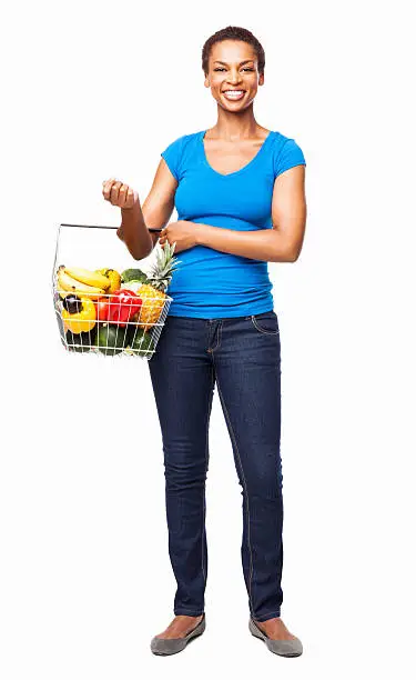 Full length portrait of a happy African American woman carrying a basket of fresh fruits and vegetables. Vertical shot. Isolated on white.