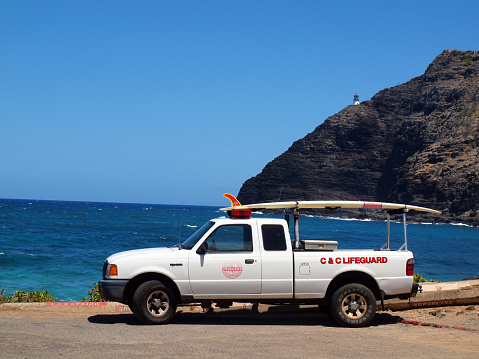Oahu - August 30, 2010: Essence of safety and adventure as a lifeguard truck stands sentinel at Makapuu Beach. With a trusty surfboard perched on its roof, this scene showcases the guardians of the shore, ready to protect and respond at a moment's notice. Against the backdrop of the sparkling ocean and clear skies, this image embodies the spirit of seaside vigilance and the allure of Oahu's natural beauty.