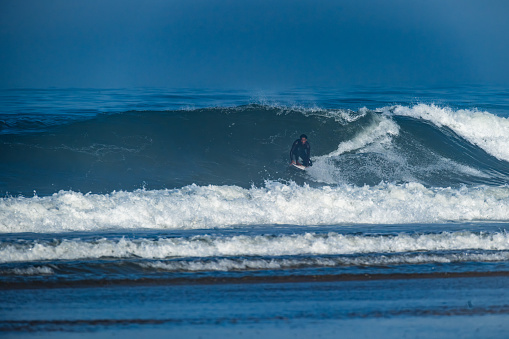 The Pacific Rim National Park on Vancouver Island on April  27, 2023:  Female engaged in surfing at Pacific Rim National Park on Vancouver Island at sunset, British Columbia