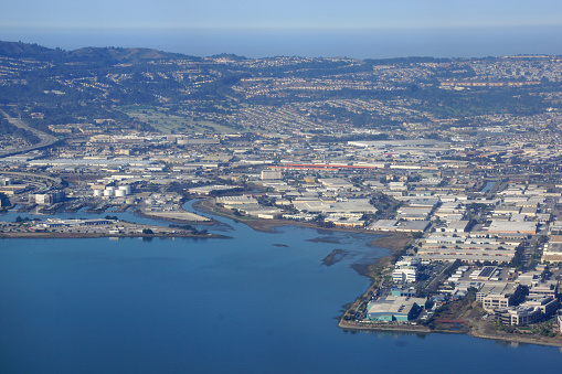 California - October 13, 2015: aerial photo of San Francisco Bay and the city skyline, showing the contrast between the urban and the natural landscapes. The photo captures the blue water of the bay, dotted with small boats, and the dense buildings and roads of the city, surrounded by hills and mountains. The sky is clear and bright, creating a beautiful backdrop for the scene.