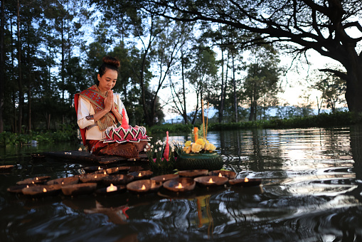 Asia women with traditional Thai dress pray to respect the water Goddess by hand made kra thong, the Loi kra thong festival in Thailand culture on November
