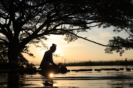 A beautiful Asian woman floats a leaf basket called Krathong in Thai to pray respect to the Goddess of Water at the river on the full moon day of November